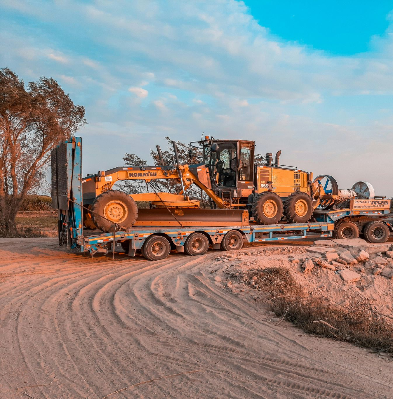 A tow truck is towing a combine harvester in a field.