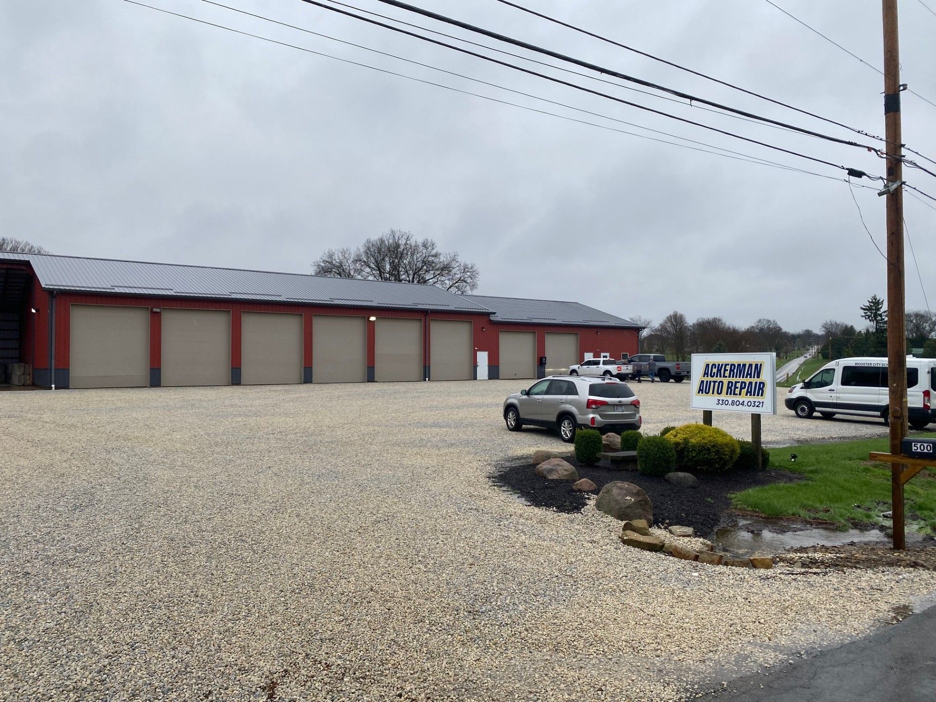 A black-and-white photo of a person in a plaid shirt, hand to their face, leaning against a brick wall.