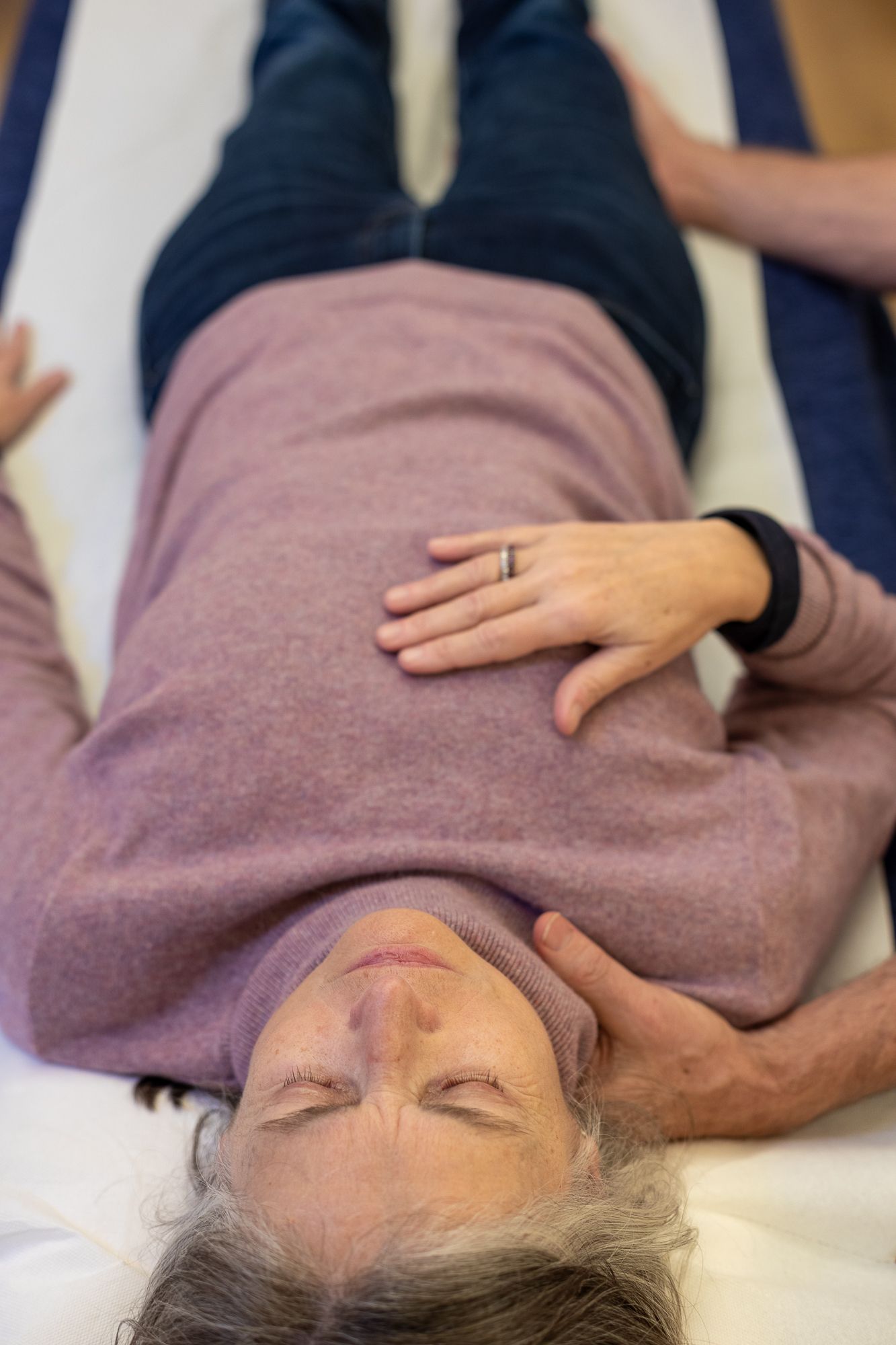 A woman is laying on her back with her eyes closed and her hands on her chest.