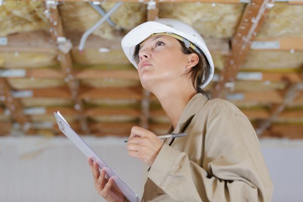A construction worker wearing a white hard hat and beige jacket. A construction worker wearing a white hard hat and beige jacket.