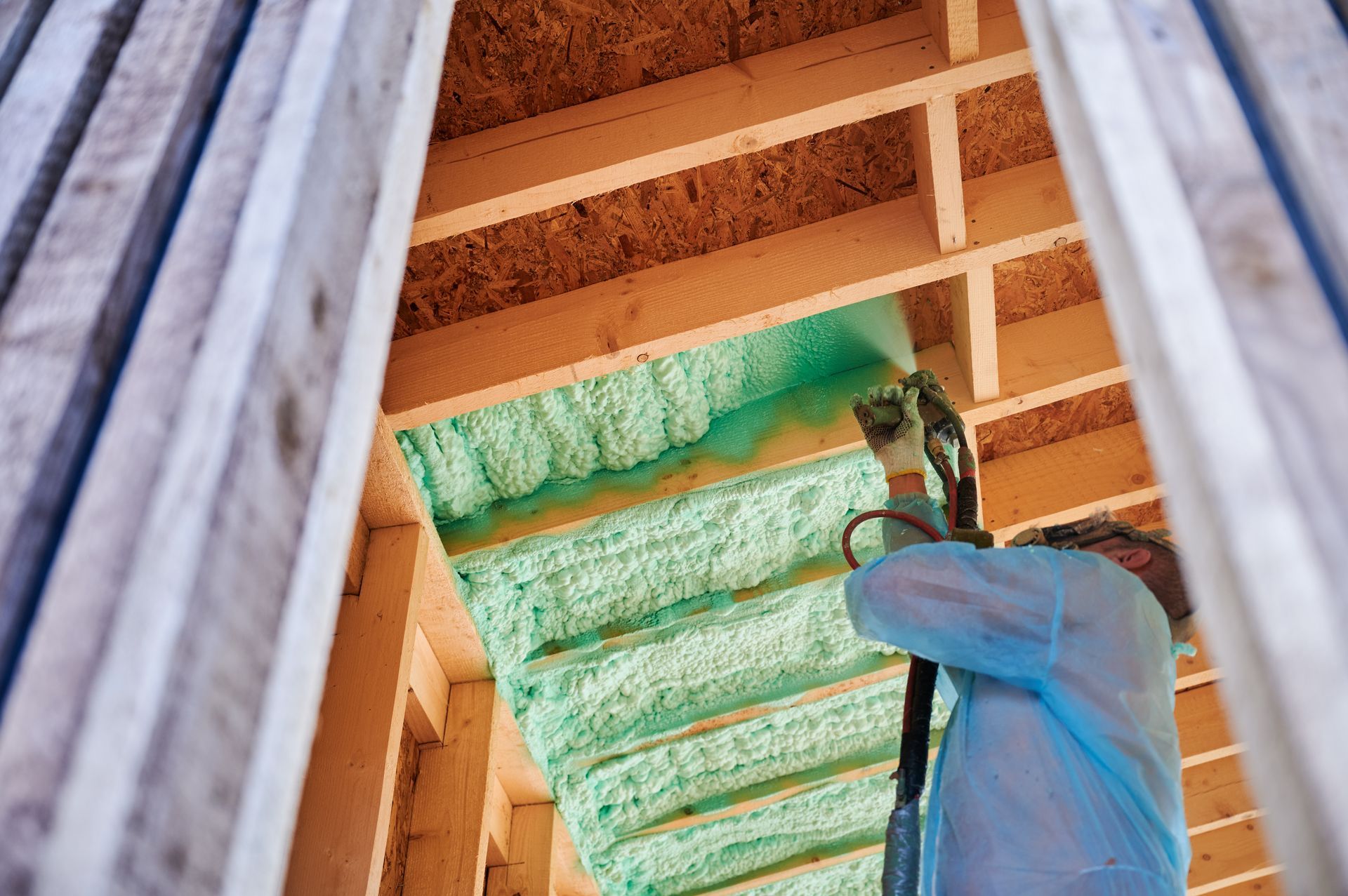 Residential insulation contractors fitting insulation in frame.