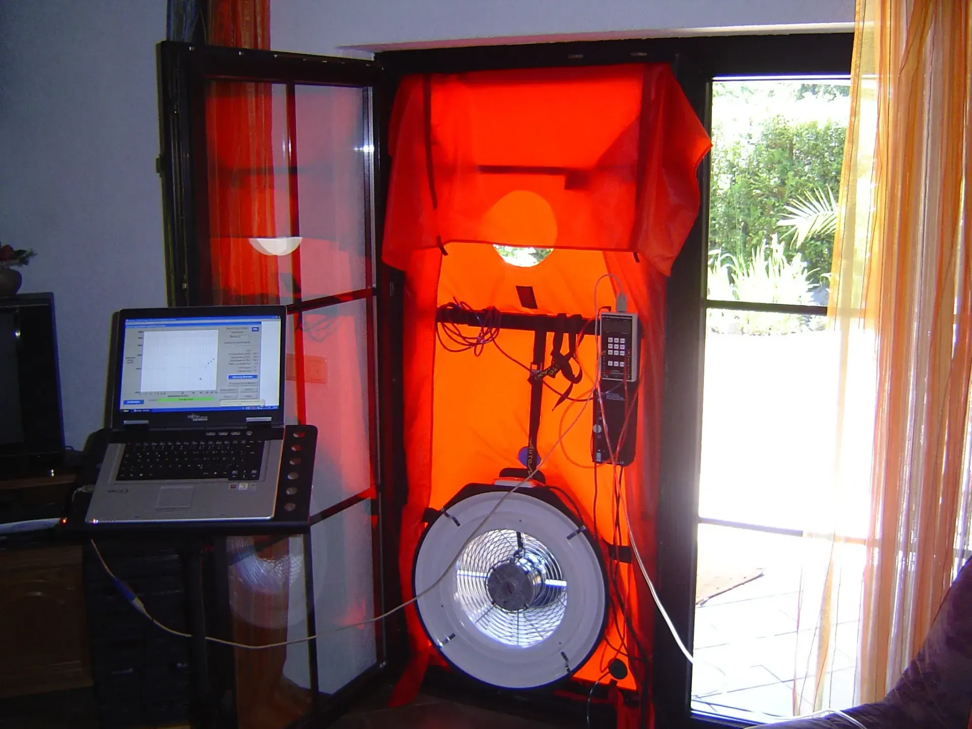 A laptop sits on a desk in front of an orange door