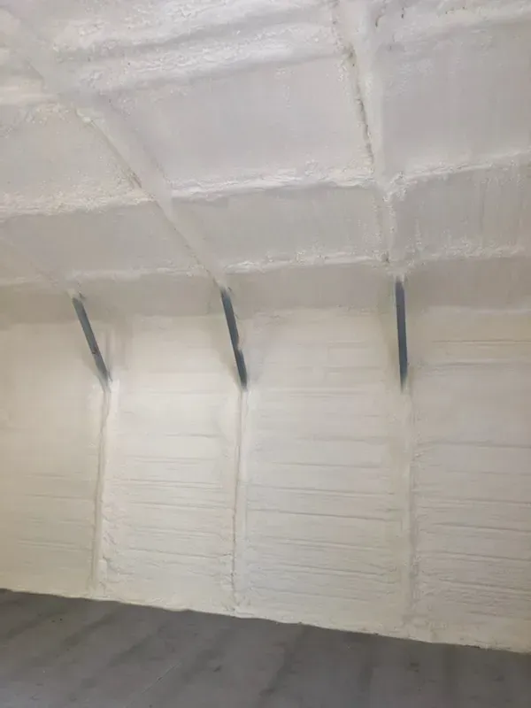 A large room with a ceiling and walls covered in white spray foam.
