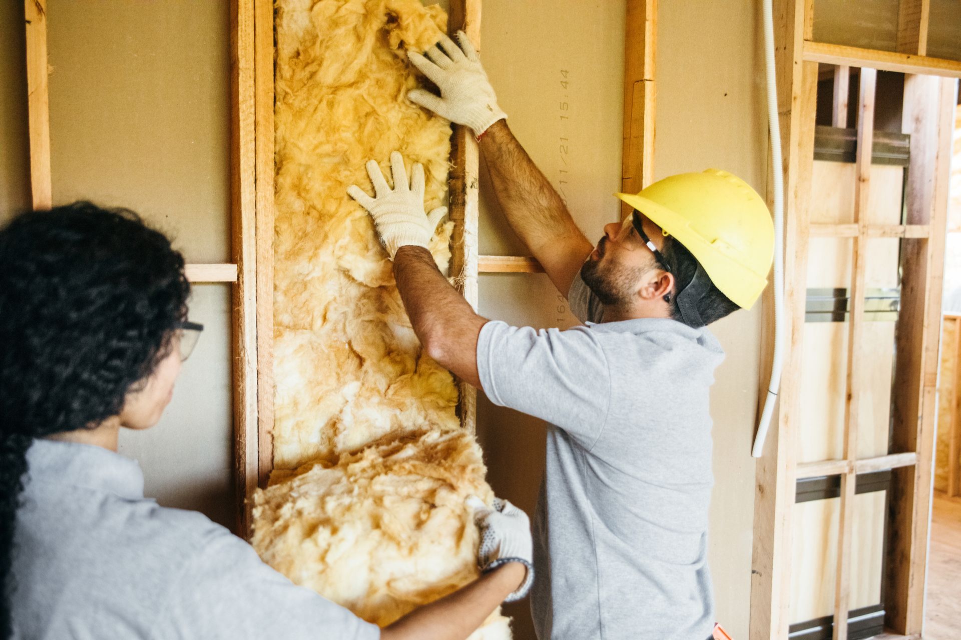 Residential insulation contractors fitting insulation in frame.