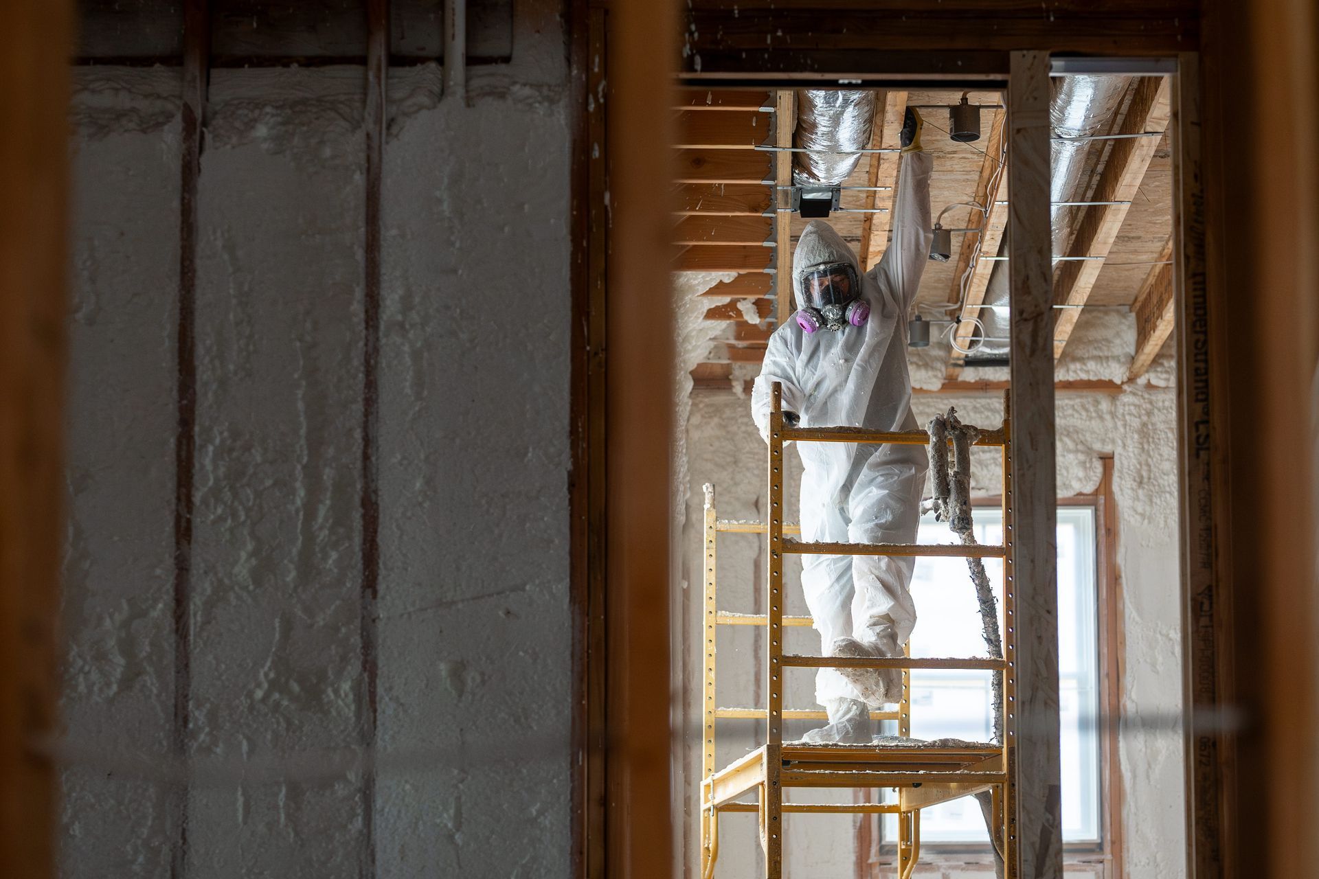 Man working on home insulation to boost energy efficiency and reduce utility costs.