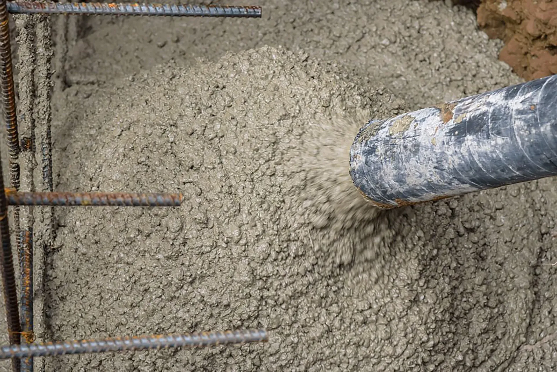 A person is pouring concrete into a hole in the ground.