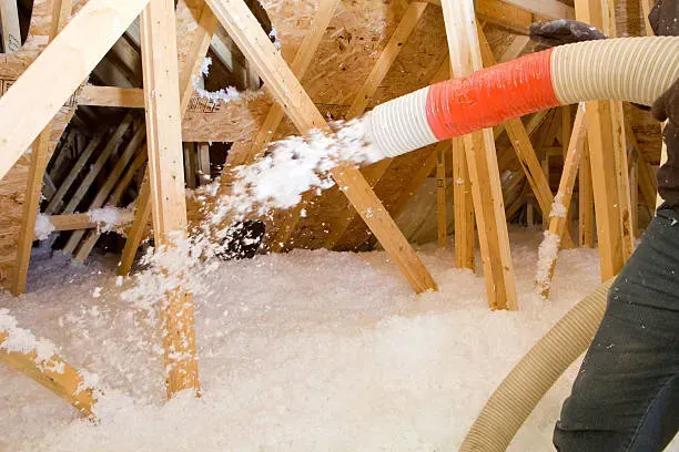 A person is blowing insulation into the attic of a house.