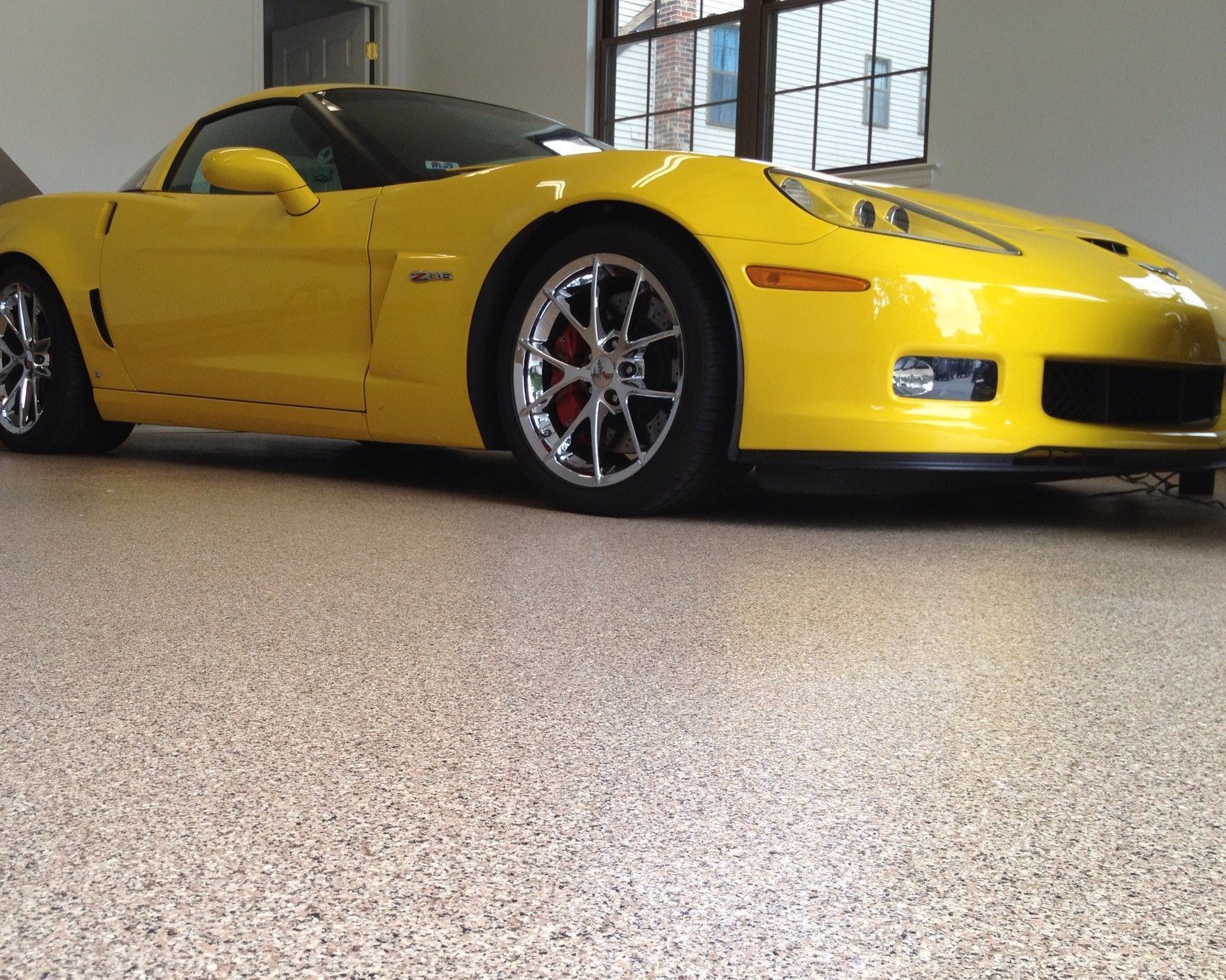 Yellow sports car parked indoors on a showroom floor, low-angle view.