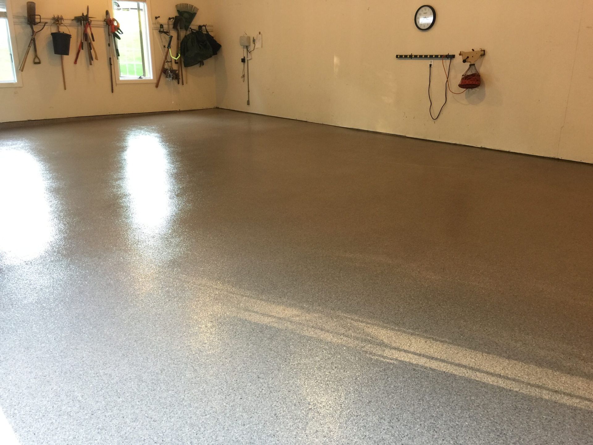 Empty garage with a freshly coated glossy gray floor and tools on the walls