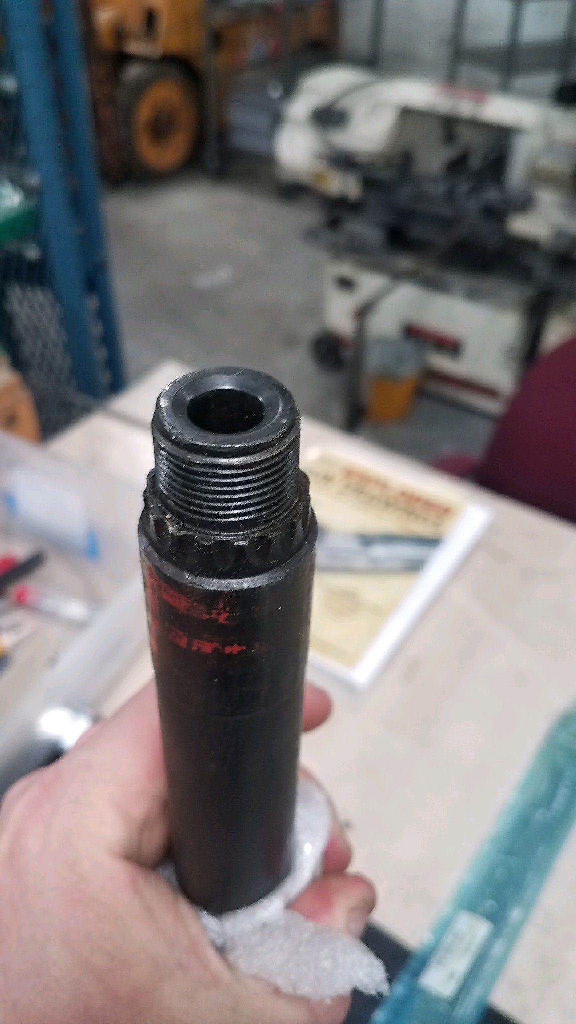 Black cylindrical tool with threads held in hand.