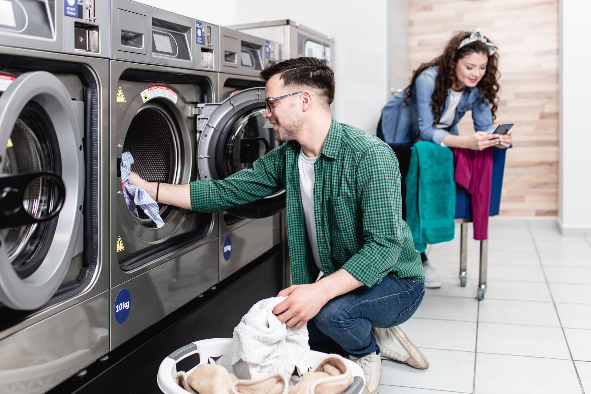 A man loading a washing machine in a laundromat