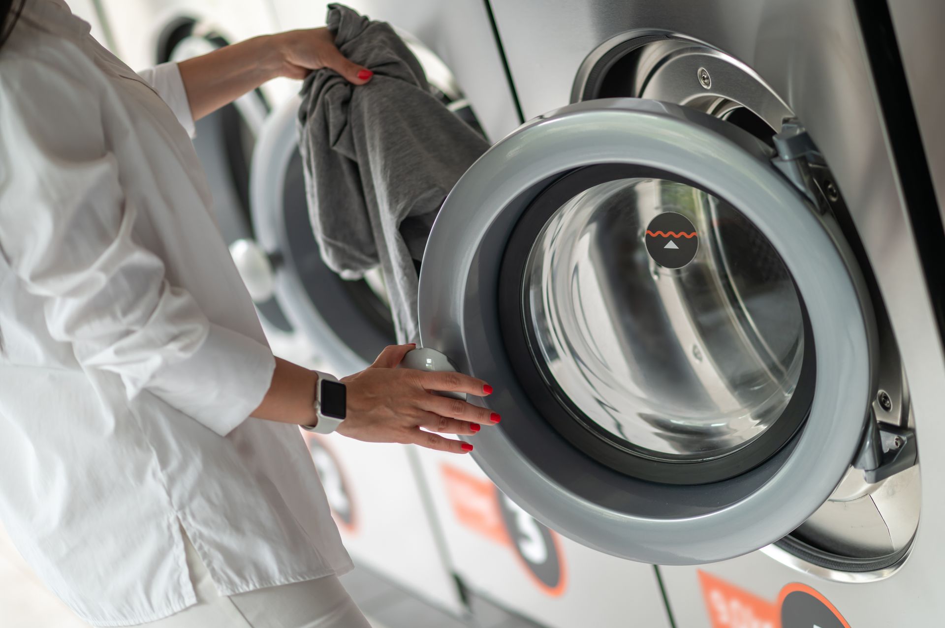 Woman loading clothes into a washing machine at a laundromat