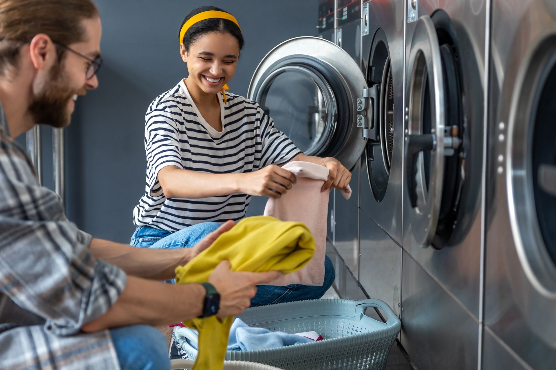 A smiling couple doing laundry at a laundromat