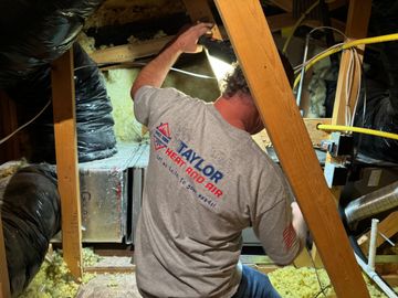 A man wearing a taylor shirt is working in an attic