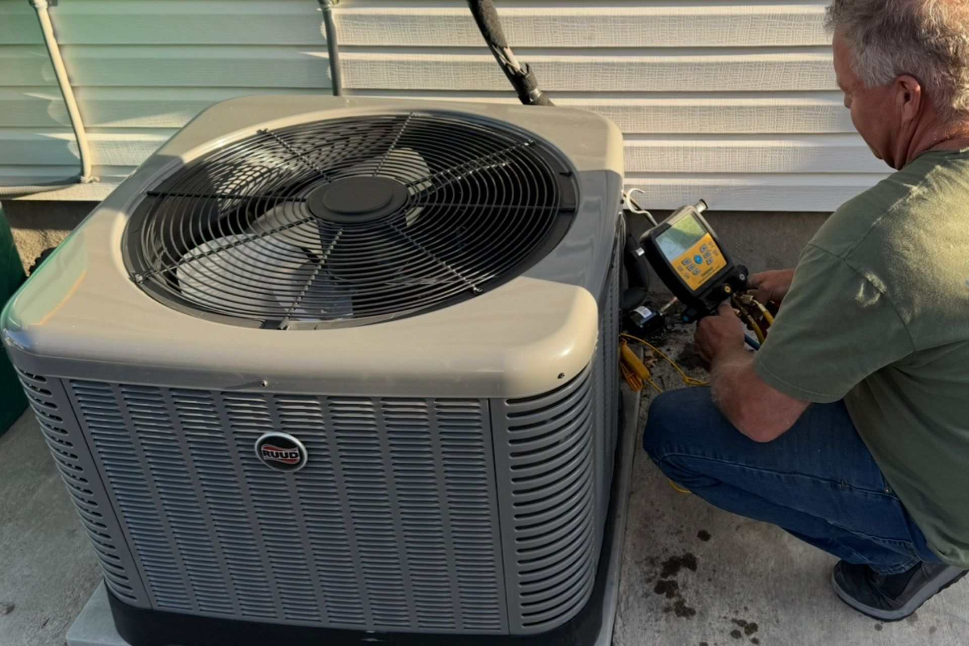 A man is working on an air conditioner on the side of a building.