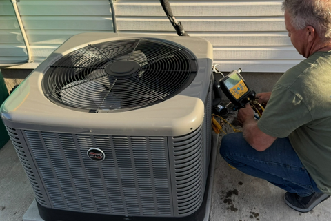A man is working on an air conditioner on the side of a building.