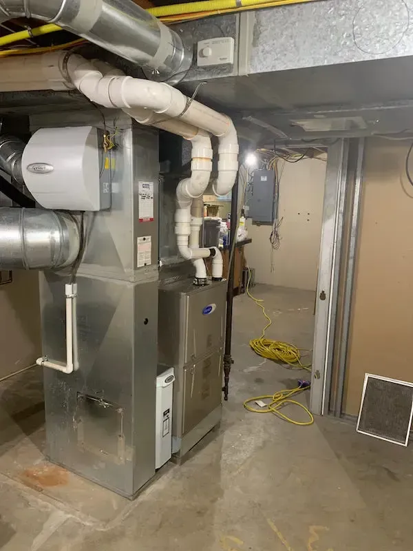 A basement with a furnace and pipes coming out of it.