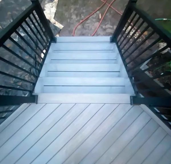 A set of stairs leading up to a deck with a black railing
