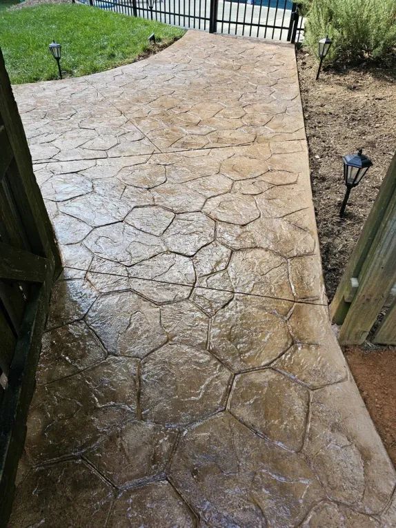 A concrete walkway leading to a fence and a pool