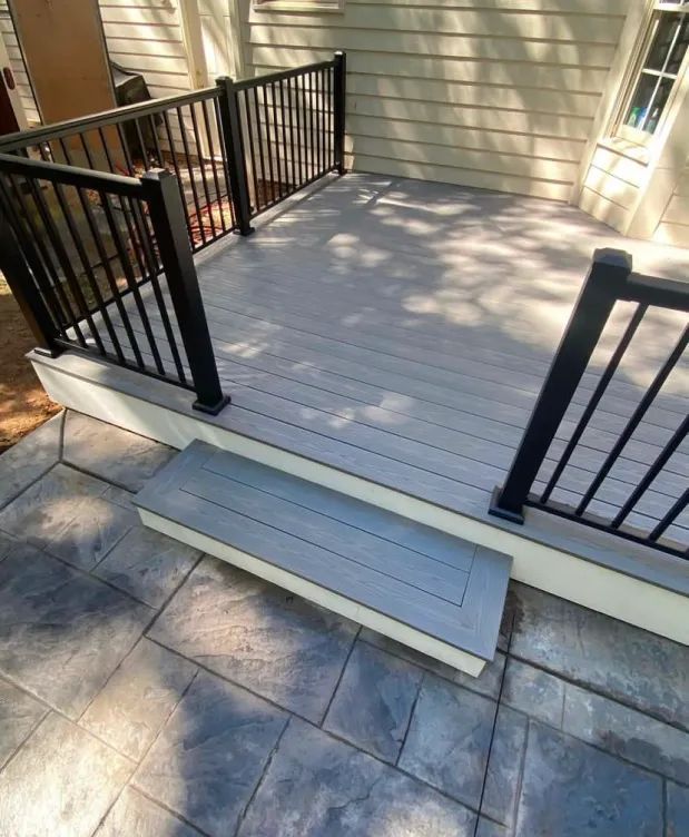 A deck with stairs and a black railing on a house