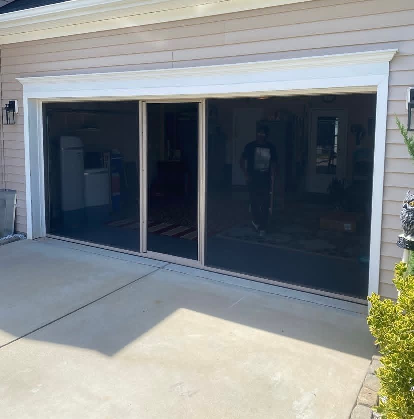 A man is standing in front of a garage door with sliding screens