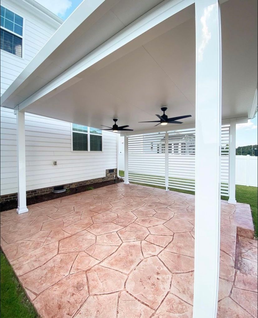 There is a covered patio with a ceiling fan in the backyard of a house