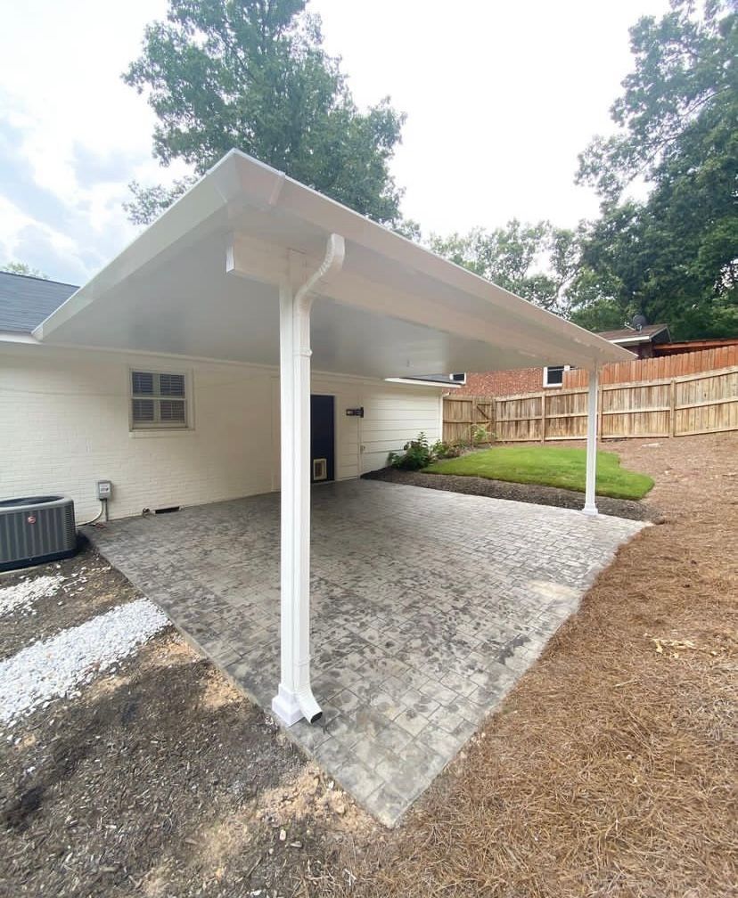 A white carport is sitting in front of a white house