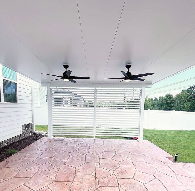 Two ceiling fans are hanging from the ceiling of a covered patio
