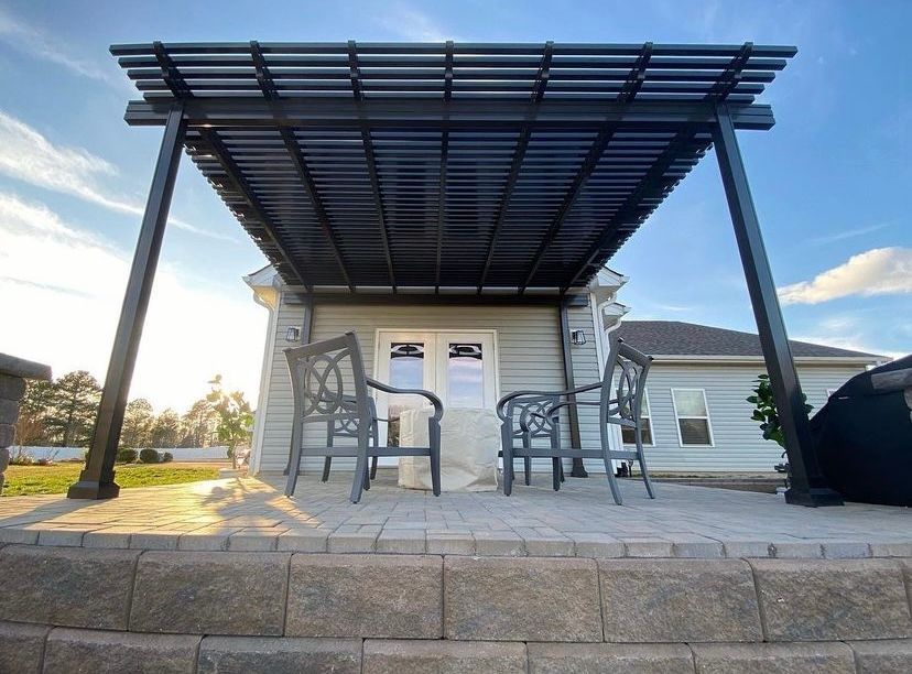A house with a pergola and chairs in front of it