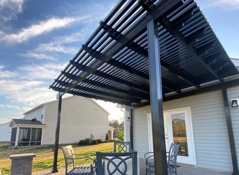 Black aluminum pergola attached to a light gray house