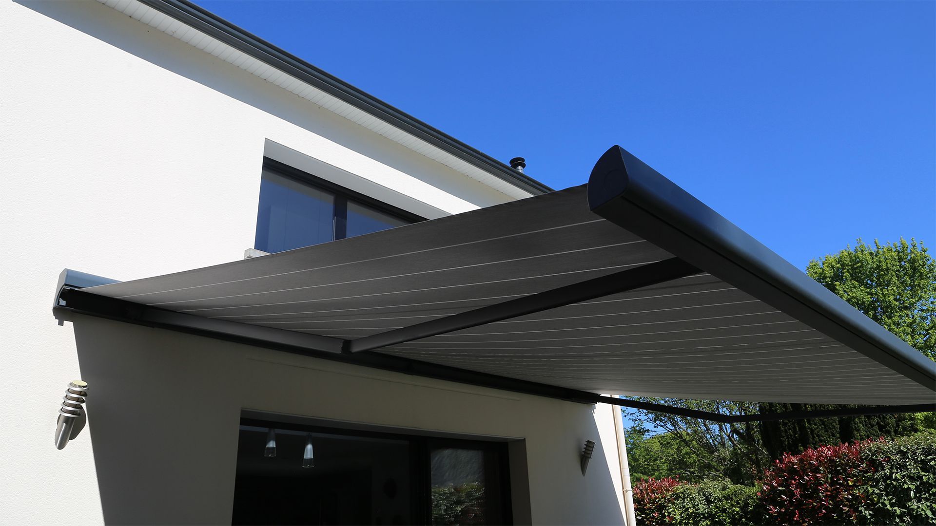Black retractable awning extended from a white building