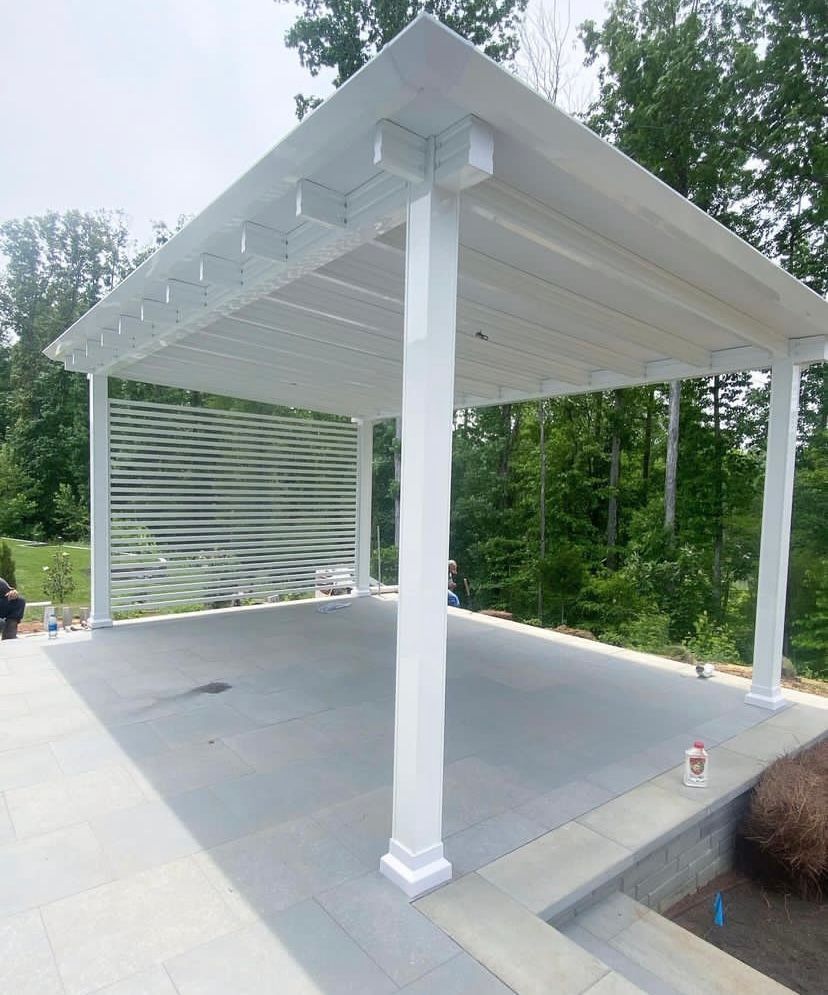 A white pergola is sitting on top of a concrete patio