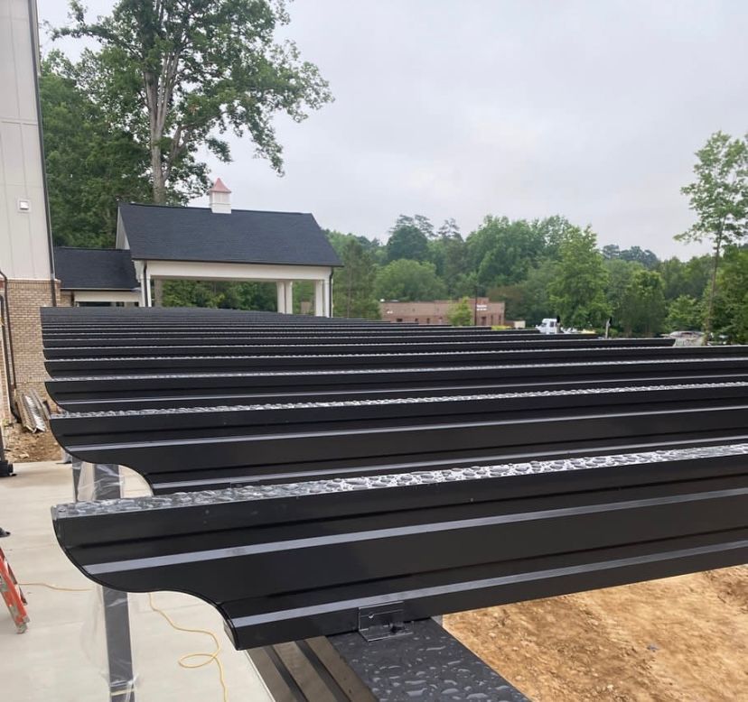 A row of black metal sheets are stacked on top of each other