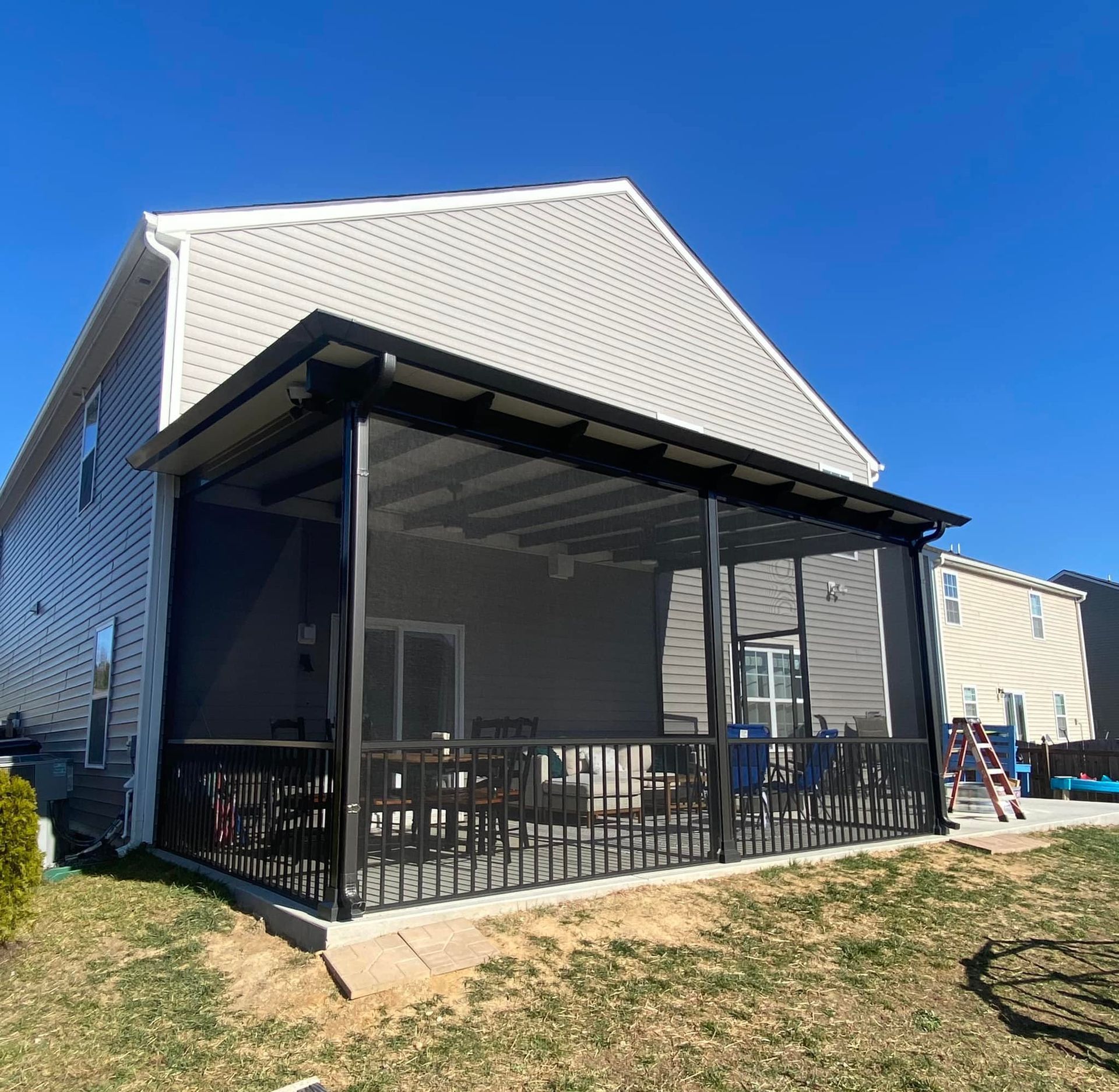 A house with a screened in porch and a ladder in front of it