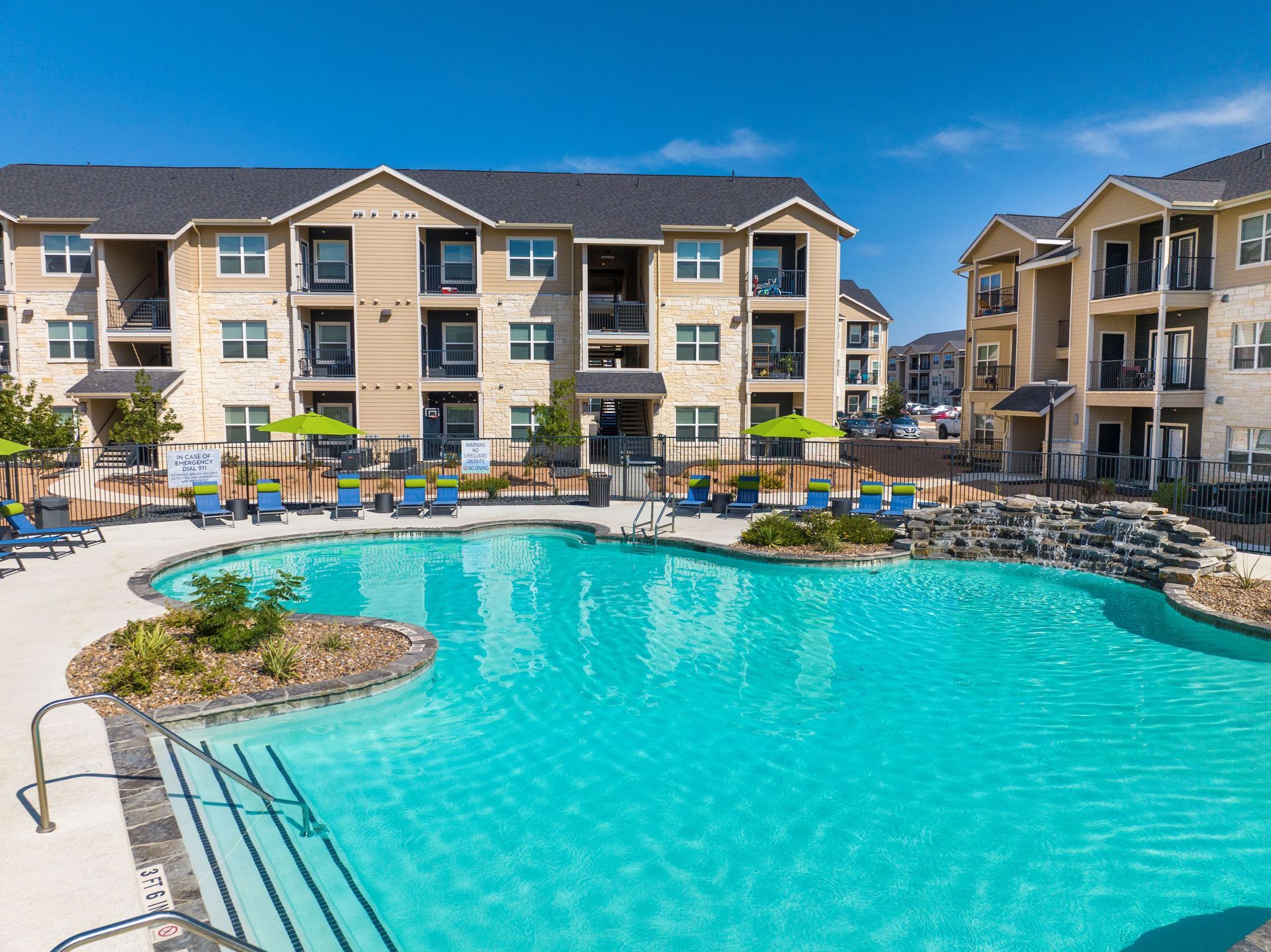 A large swimming pool in front of a large apartment building.