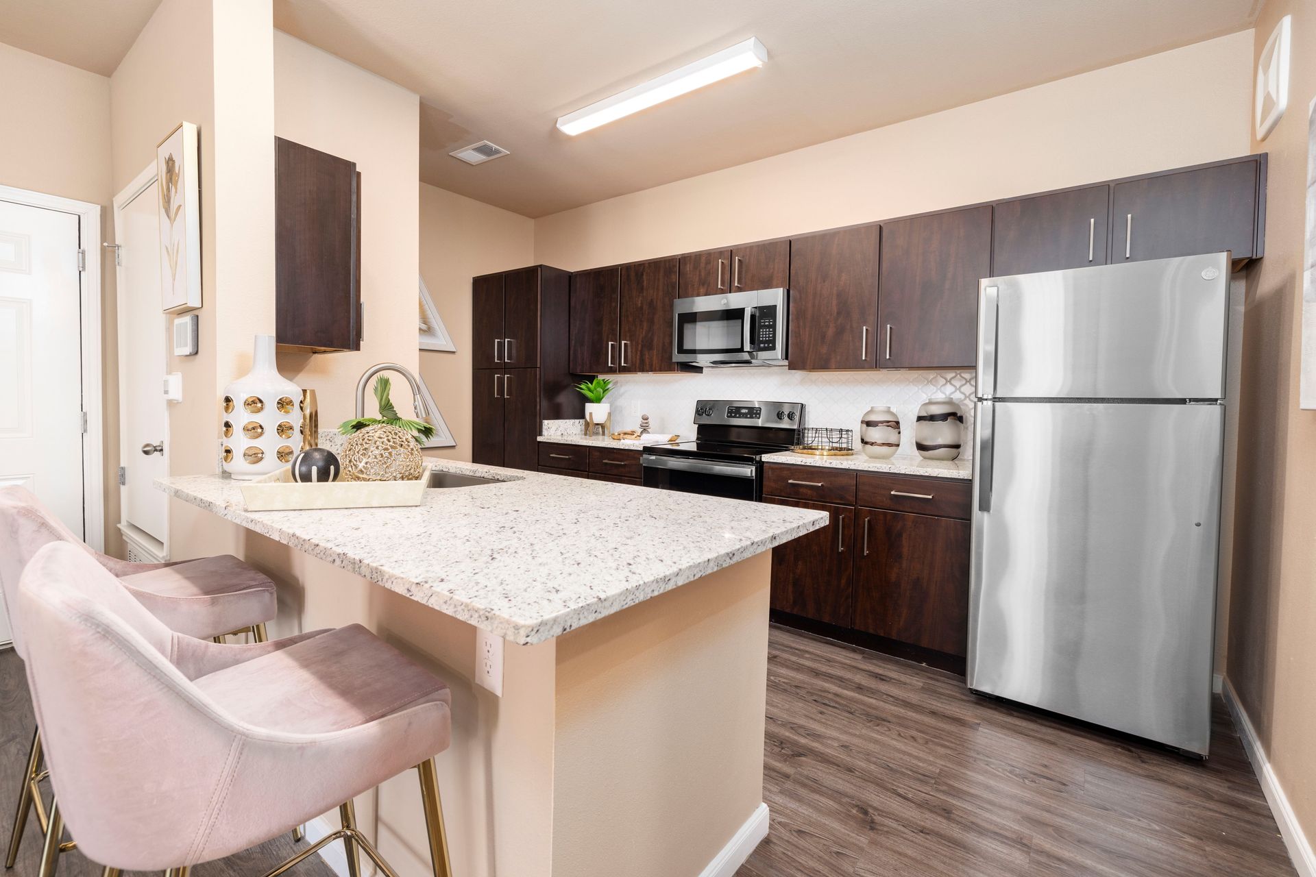 A kitchen with a sink , stove , microwave and refrigerator.