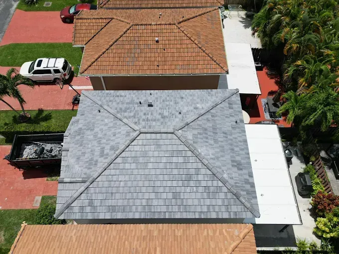 Overhead view of several residential roofs; one has gray shingles, others have orange/brown tiles.