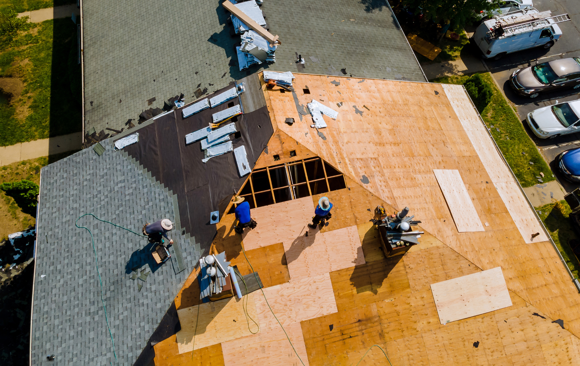 Roofers replacing a shingle roof on a house, view from above.