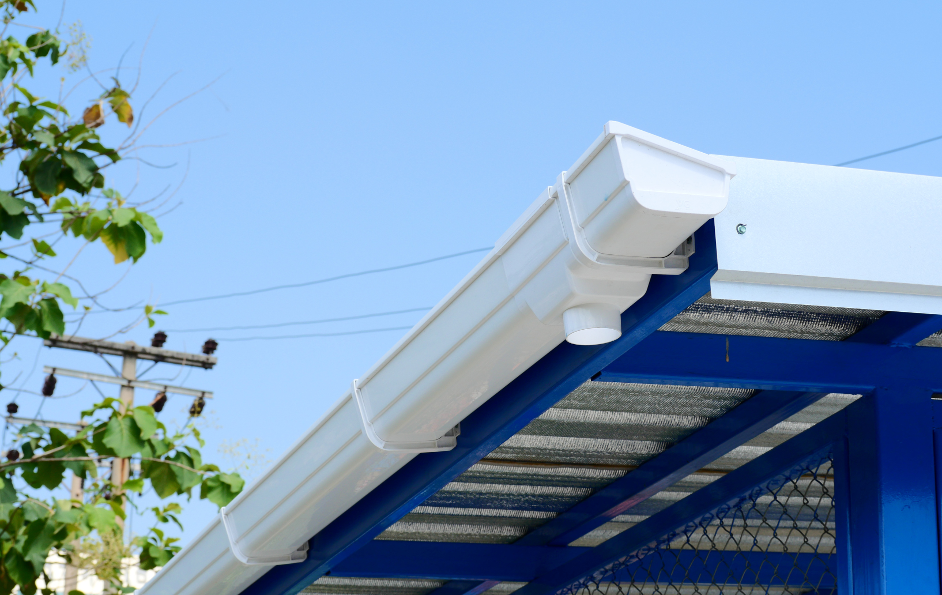 White rain gutter on a blue structure with a blue sky background.