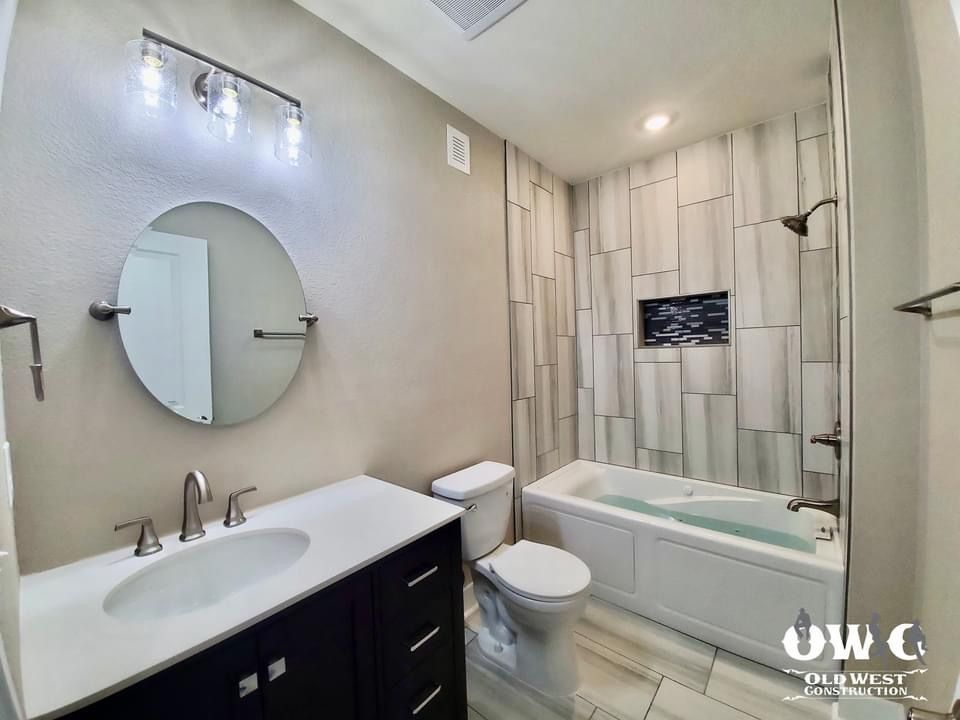 A bathroom with a sink , toilet , bathtub and mirror.