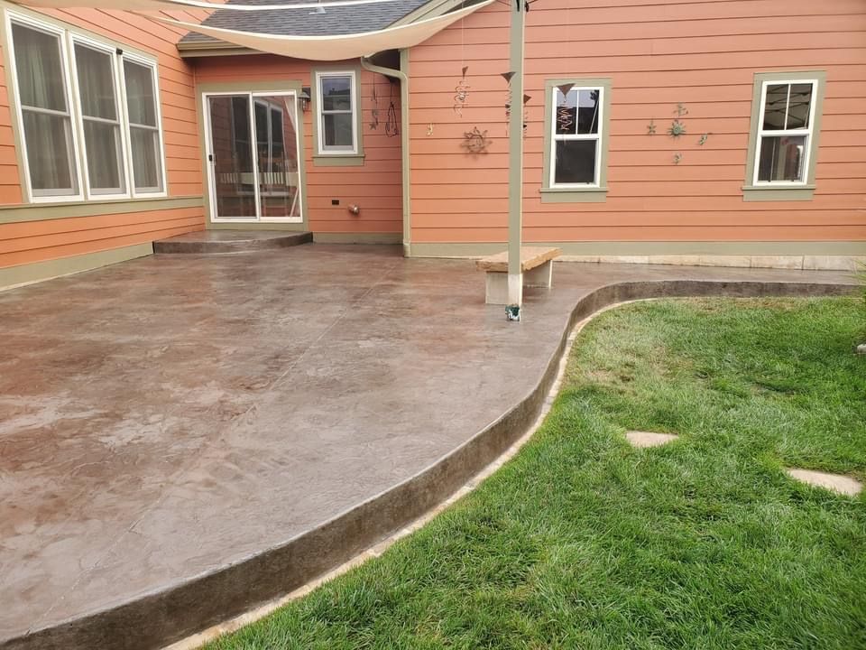 A backyard with a patio and a house in the background