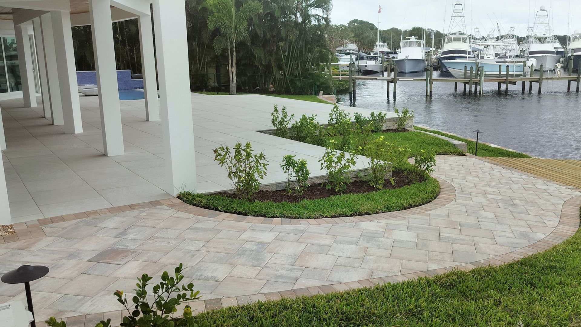 Patio with brick path, landscaping, and boats at a dock.