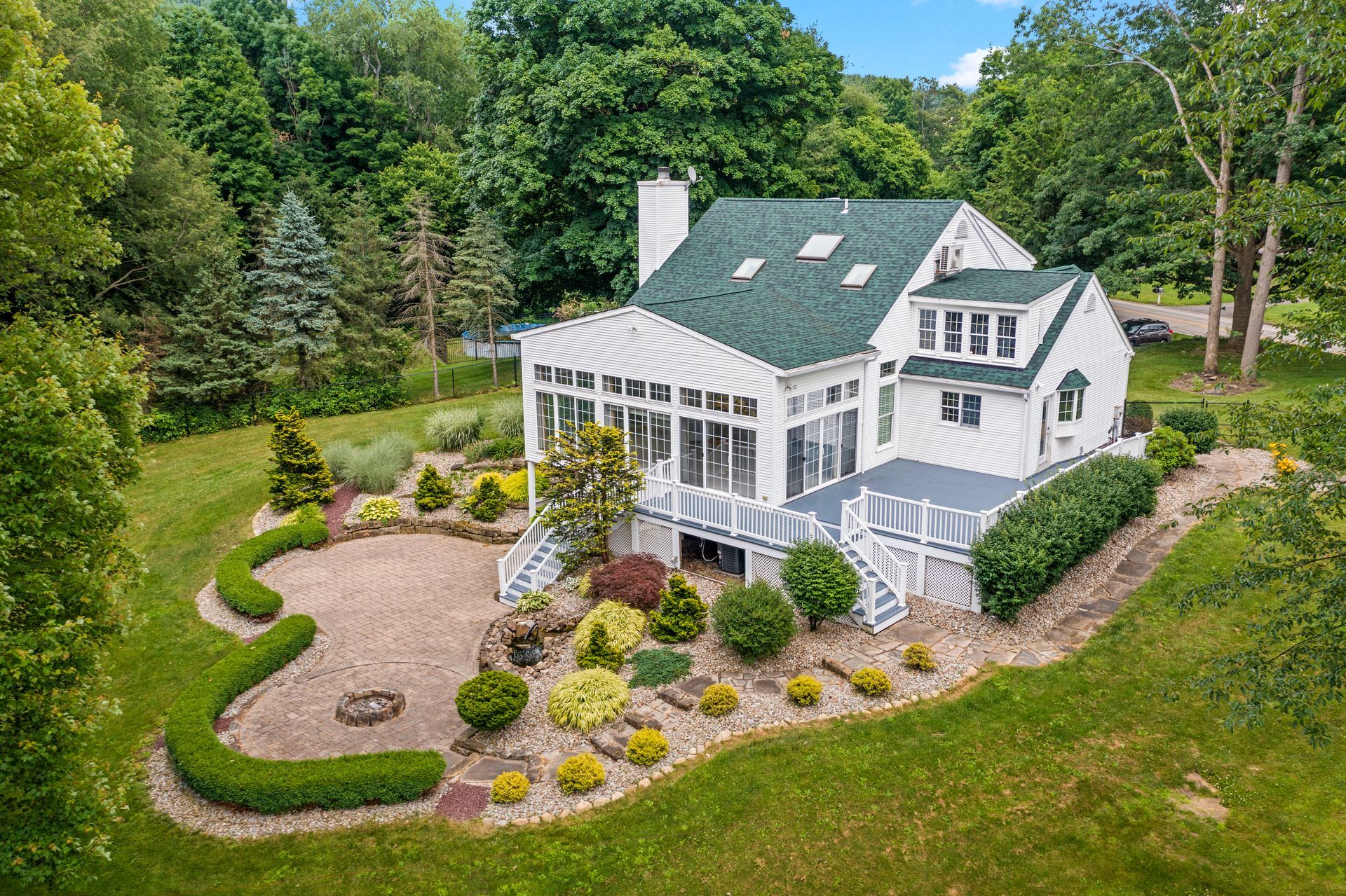 An aerial view of a large white house with a green roof surrounded by trees.