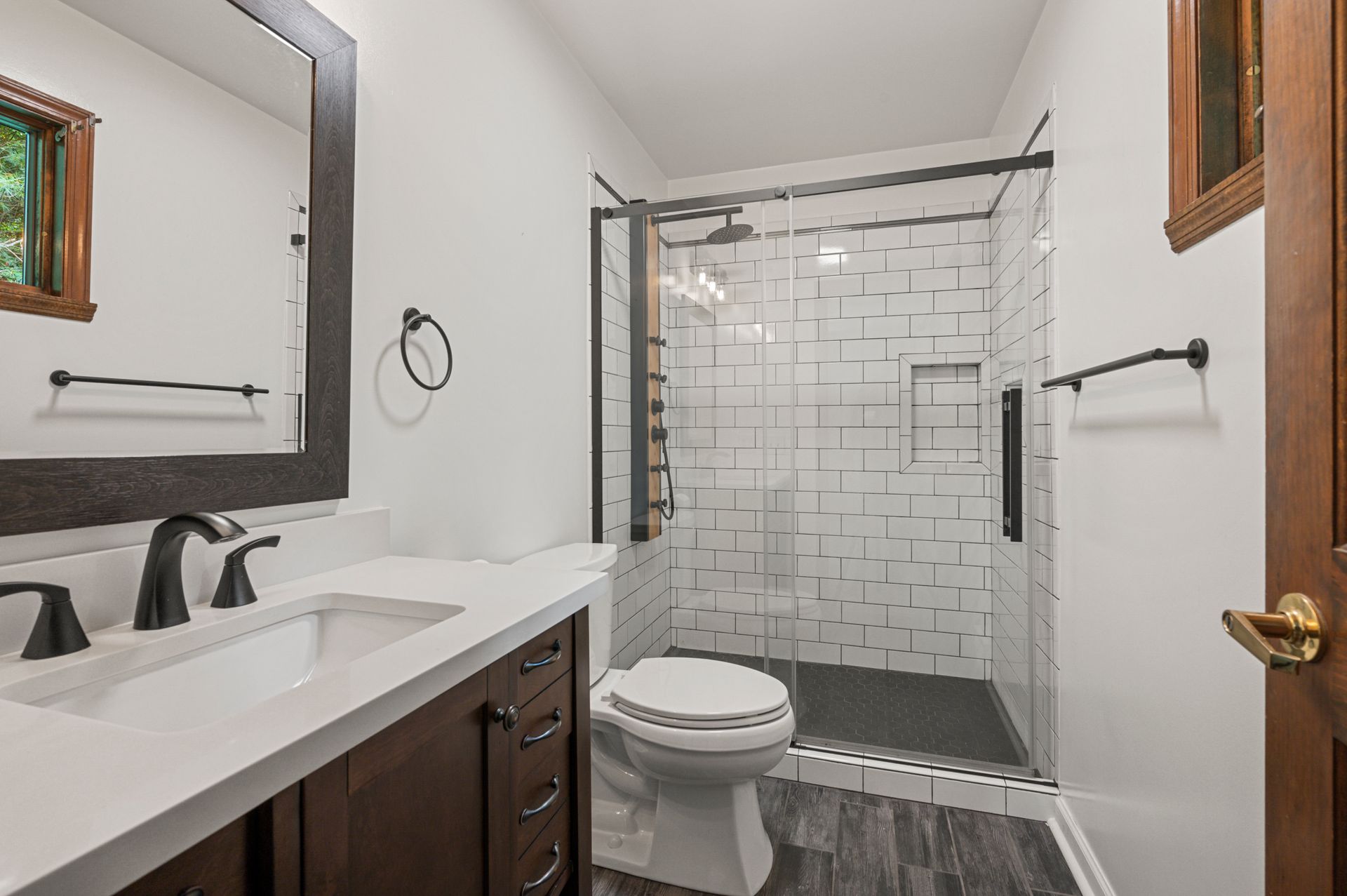 A bathroom with a toilet , sink , mirror and walk in shower.