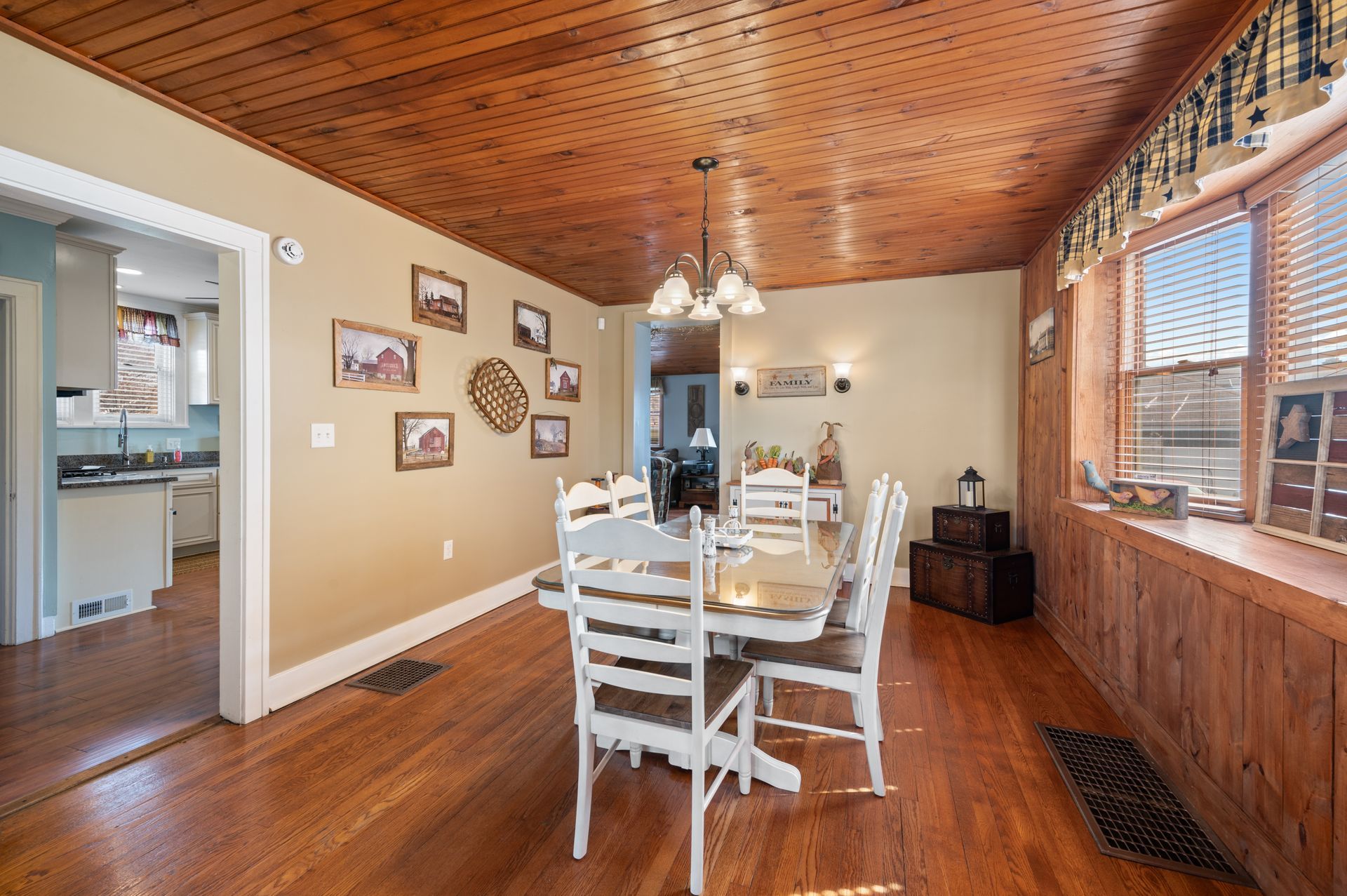 A dining room with a table and chairs and a wooden ceiling.