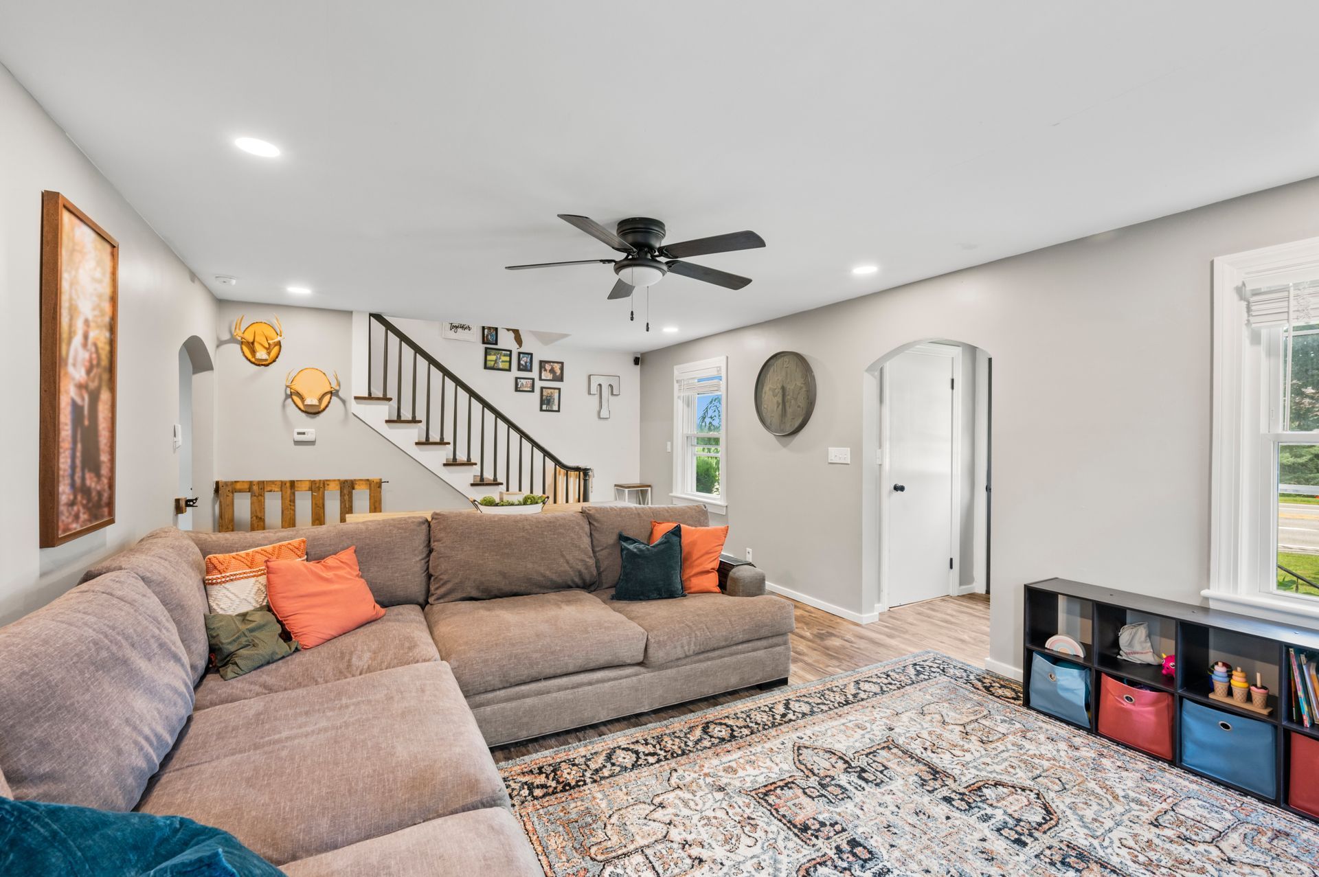 A living room with a large sectional couch and a ceiling fan.
