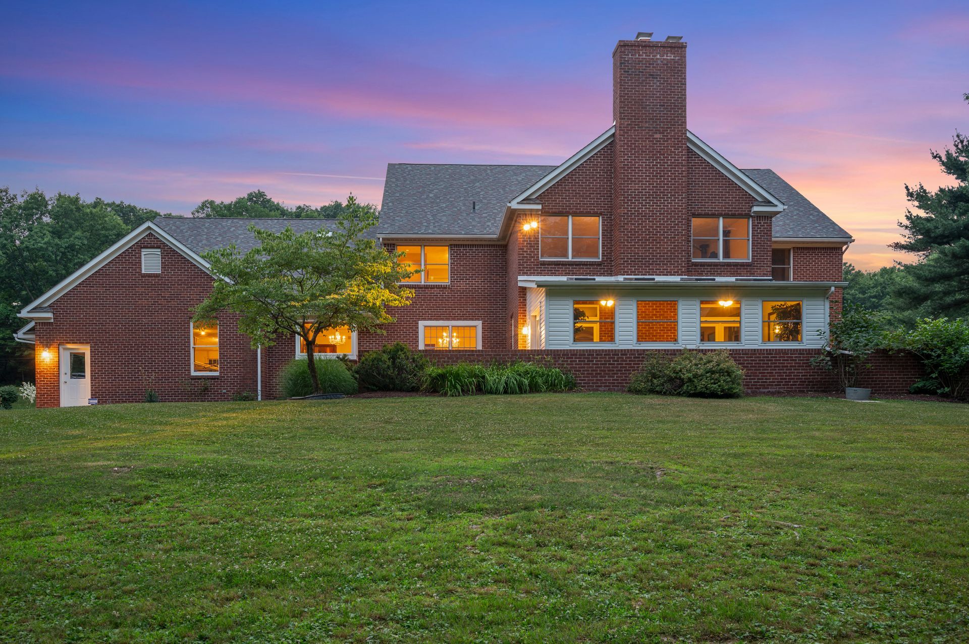 A large brick house with a large lawn in front of it