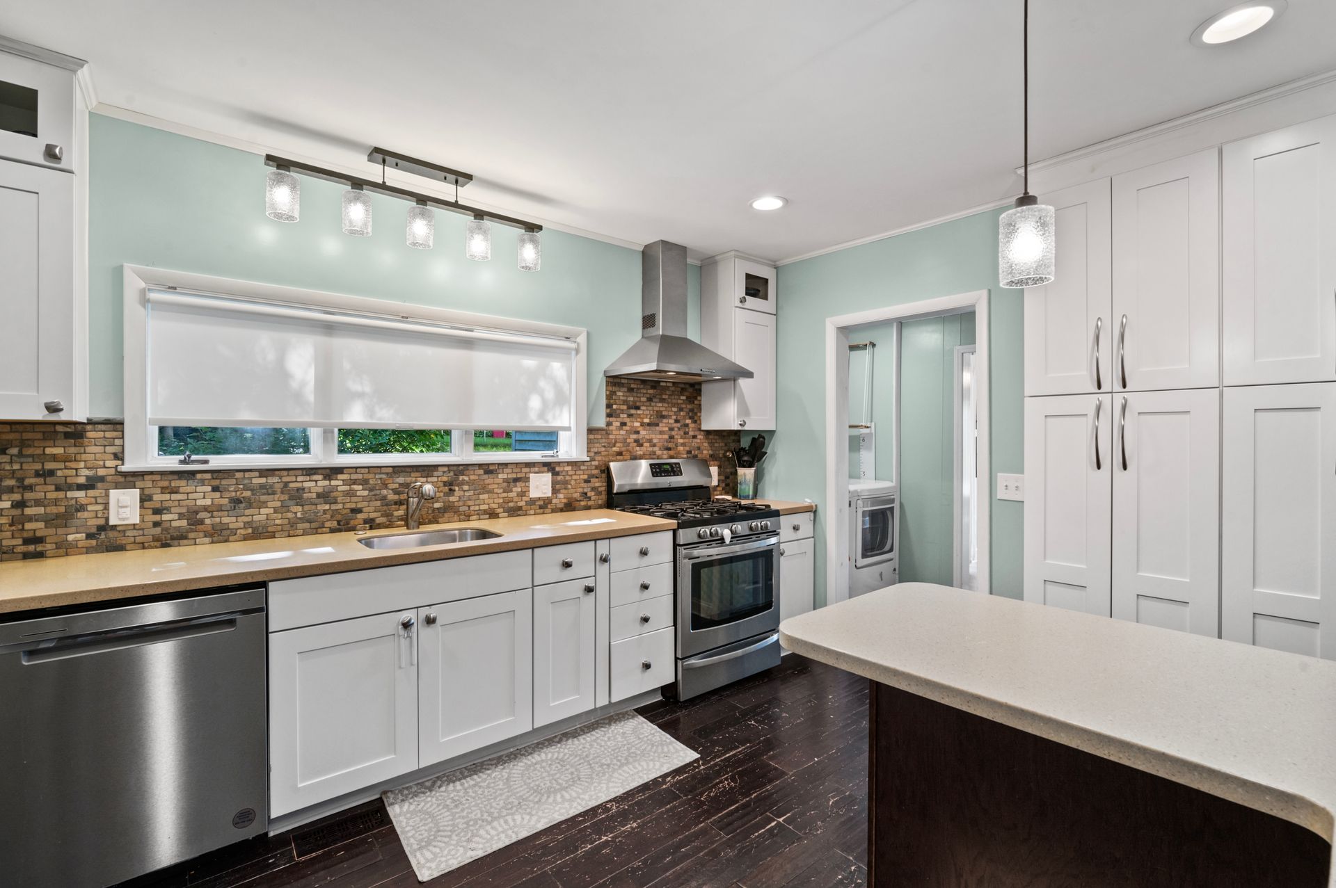 A kitchen with white cabinets , stainless steel appliances , and a large island.