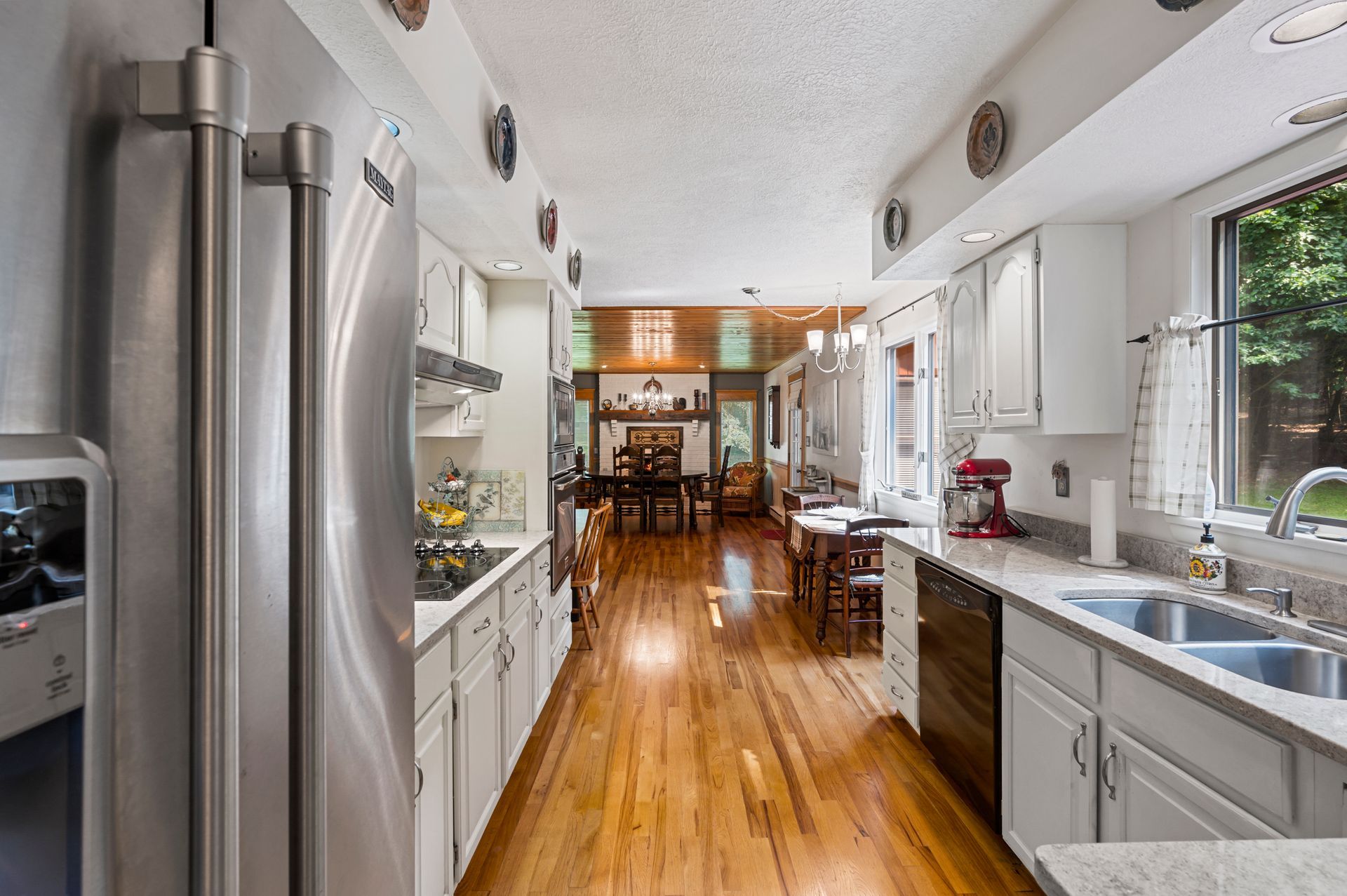 A kitchen with stainless steel appliances , white cabinets and hardwood floors.