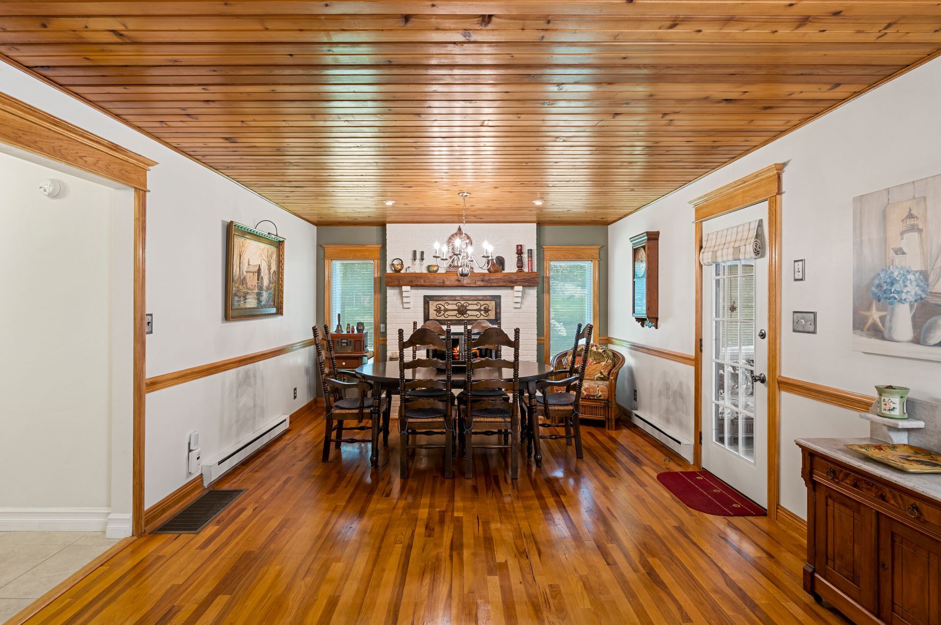 A dining room with a wooden table and chairs and a fireplace.